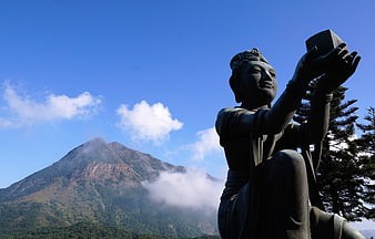 Bronze Statue of Goddess with Mountain and Blue Sky Background