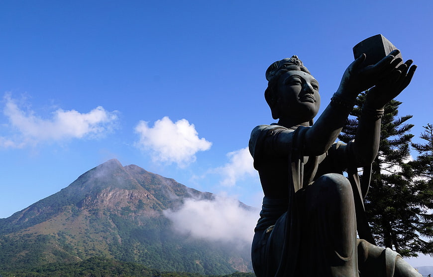 Bronze Statue of Goddess with Mountain and Blue Sky Background
