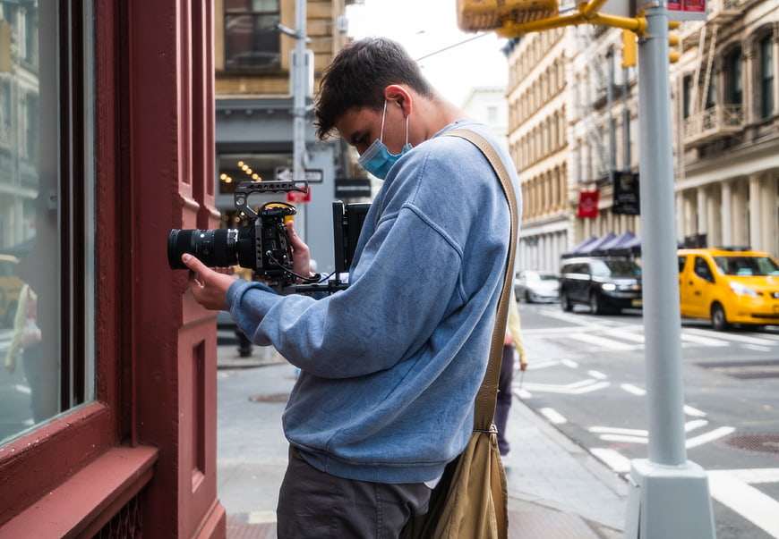 Cameraman filming on city street with professional camera