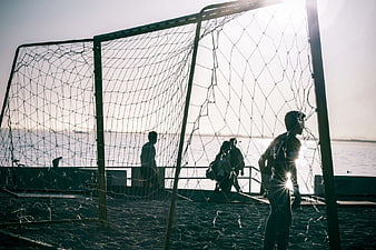 Silhouettes of People Playing Football on Beach at Sunset