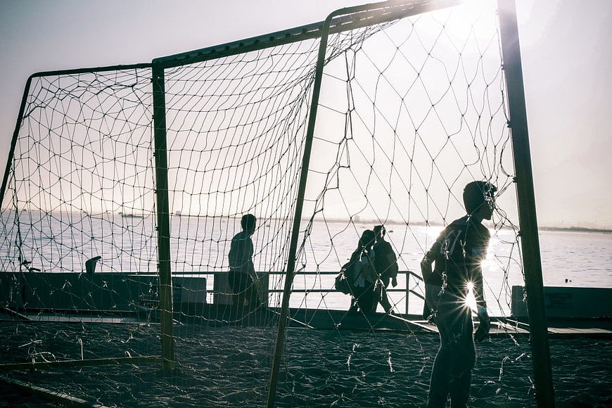 Silhouettes of People Playing Football on Beach at Sunset
