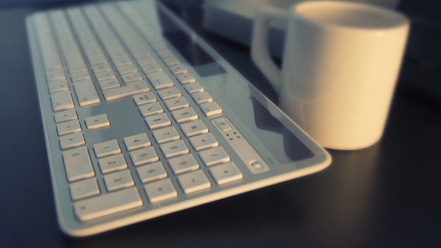 White Keyboard and Coffee Mug on Dark Desk