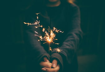 Person holding lit sparkler at night