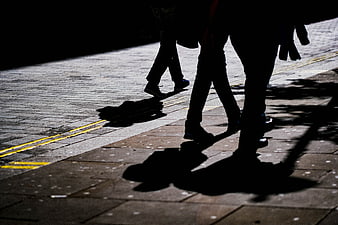 Silhouettes of people walking on a paved street at night