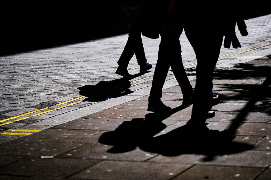 Silhouettes of people walking on a paved street at night