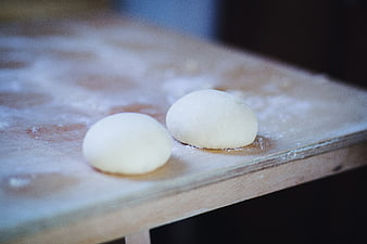 Two balls of raw dough on a floured wooden board