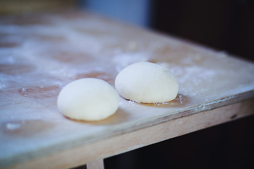 Two balls of raw dough on a floured wooden board