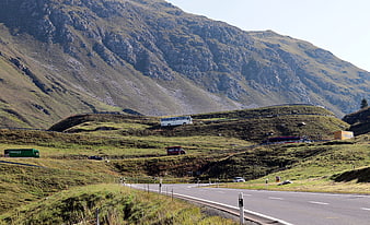 Mountain Road With Buses And Trucks In Green Alpine Landscape