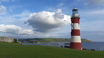 Red and White Lighthouse on Green Hill Overlooking Harbor