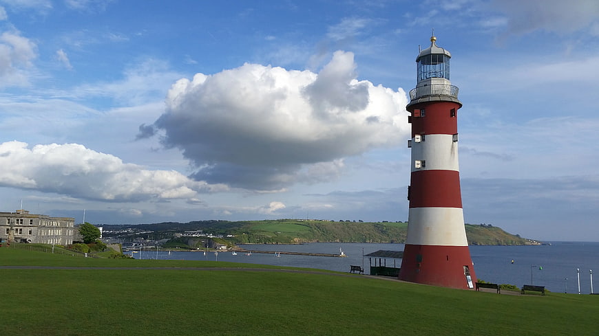 Red and White Lighthouse on Green Hill Overlooking Harbor