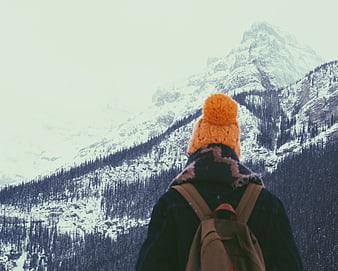 Hiker in Orange Beanie Looking at Snowy Mountain Peak