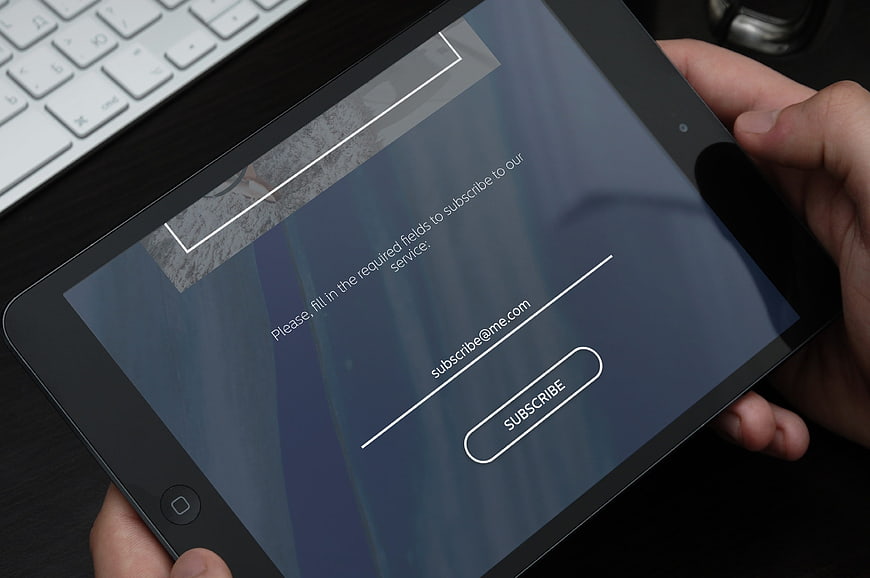 Hands holding tablet with email subscription form interface
