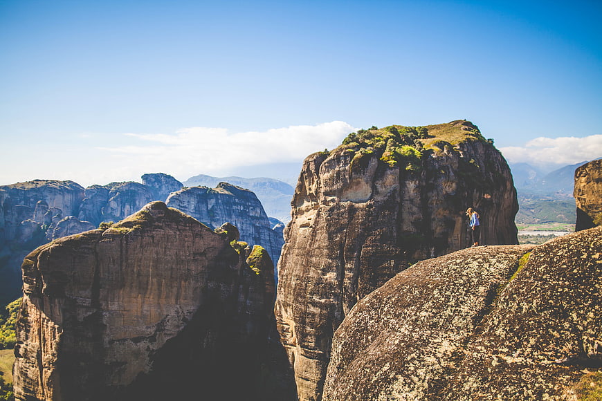 Woman standing on top of towering rock formation in Meteora, Greece