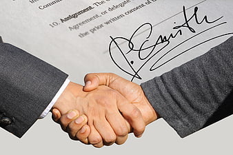 Business Handshake Over Signed Contract Agreement