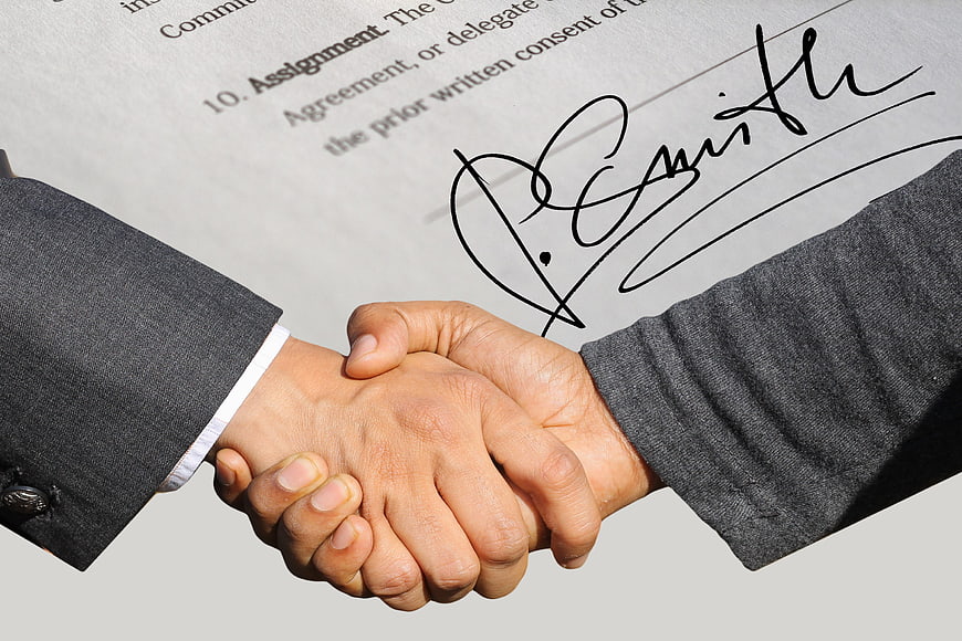 Business Handshake Over Signed Contract Agreement