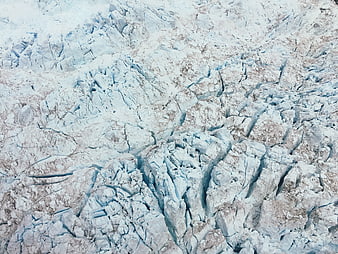 Aerial view of cracked glacier ice surface with blue crevasses