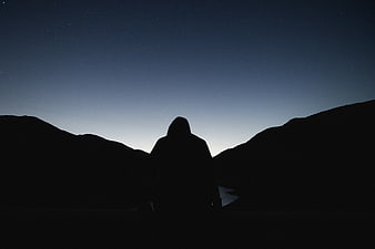 Silhouette of Hooded Figure Against Starry Night Sky
