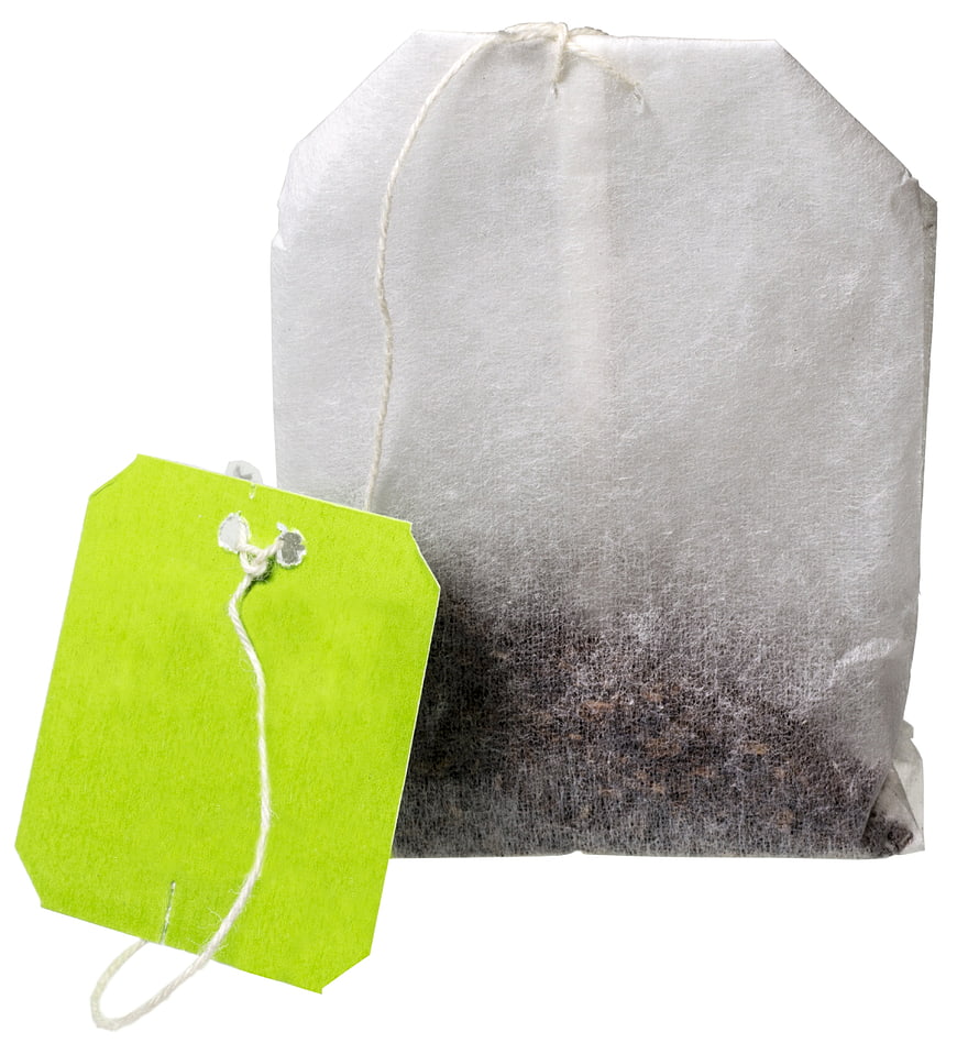 White paper teabag with green tag on white background
