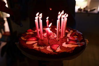 Homemade birthday cake with lit candles and strawberries