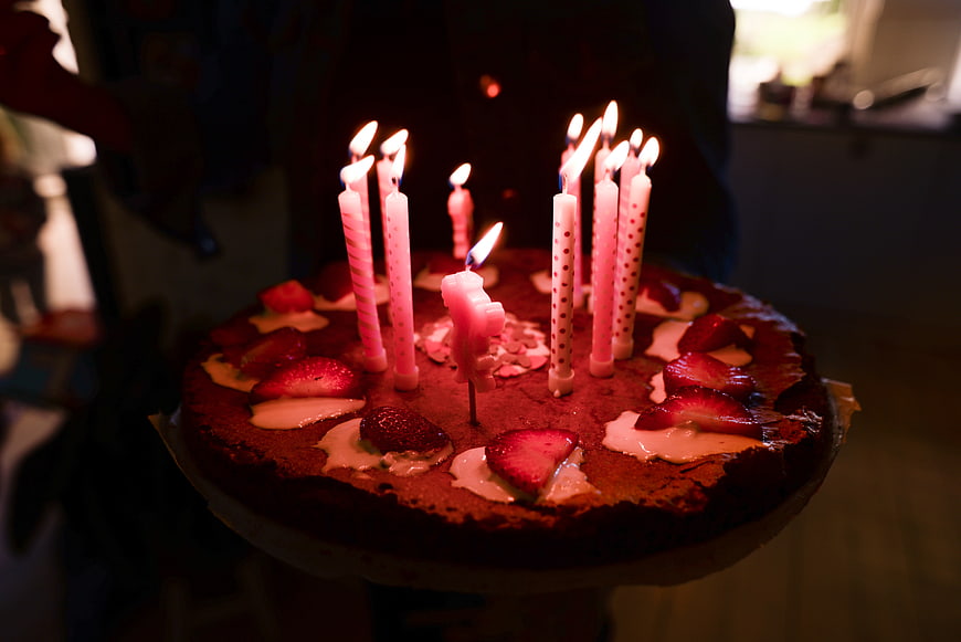 Homemade birthday cake with lit candles and strawberries
