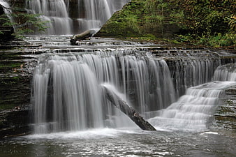 Serene tiered waterfall cascading over mossy rocks in forest