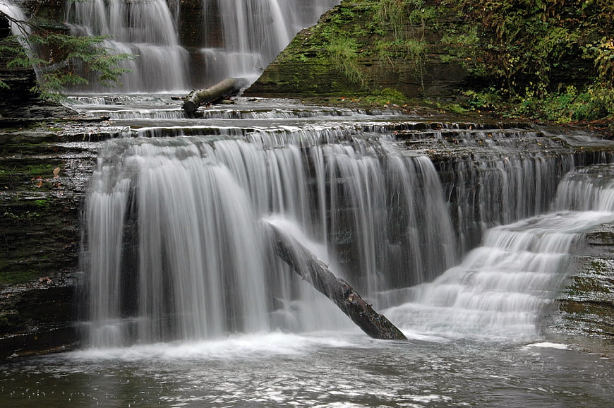 Serene tiered waterfall cascading over mossy rocks in forest