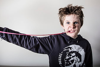 Boy with spiky hair stretching pink chewing gum