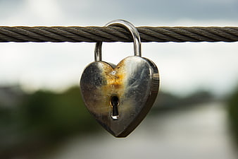 Rusty heart-shaped padlock on steel cable