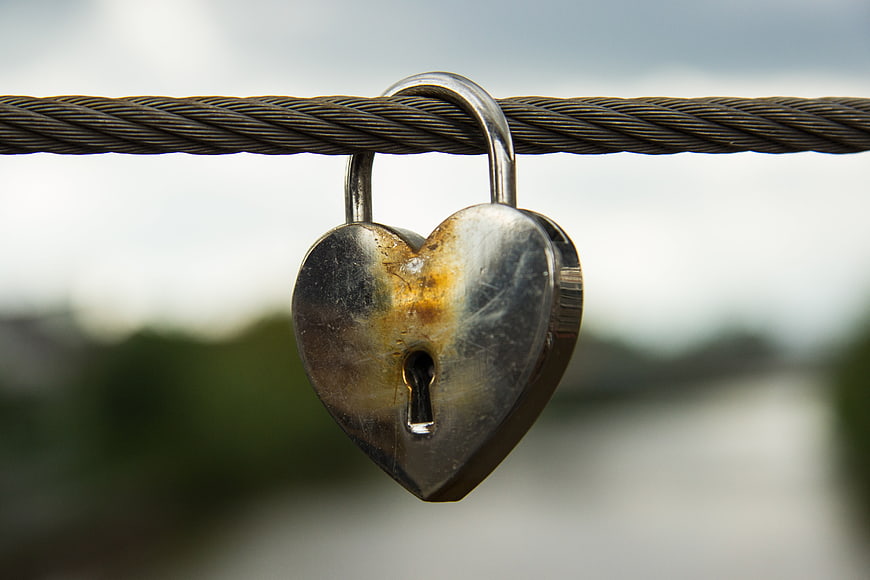 Rusty heart-shaped padlock on steel cable