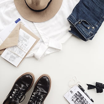 Flat lay of casual outfit with white shirt, jeans, and boots