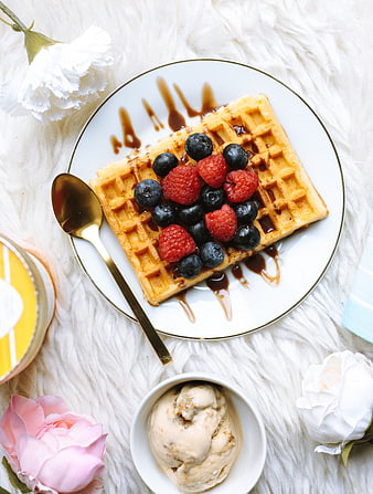 Overhead view of waffles with berries and ice cream on white fur