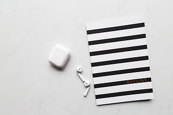 Minimalist flat lay of wireless earbuds and striped notebook