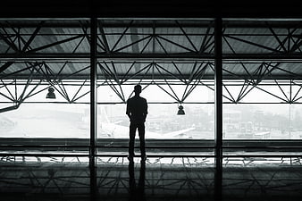 Silhouette of man looking out airport terminal window