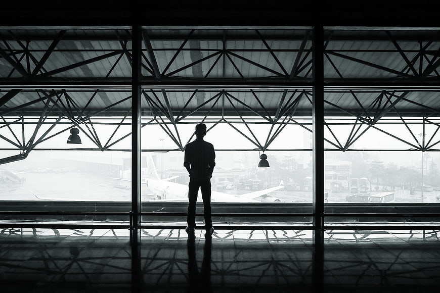 Silhouette of man looking out airport terminal window