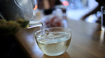 Pouring Clear Tea into Glass Cup on Wooden Table