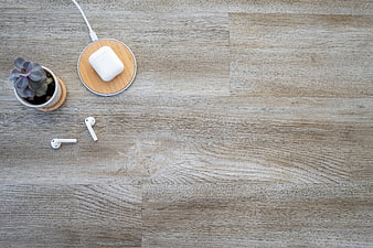 Minimalist workspace with wireless earbuds and succulent on wood