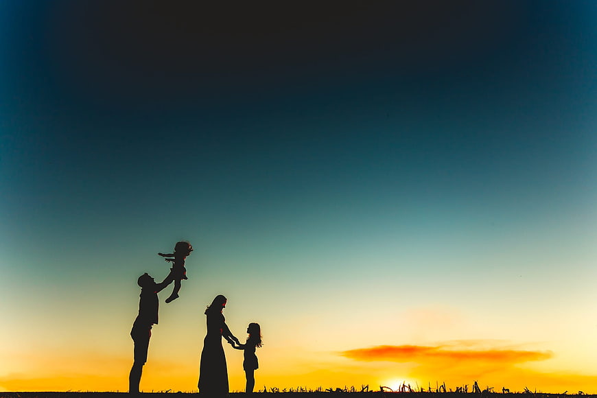 Silhouette of family playing at sunset in field