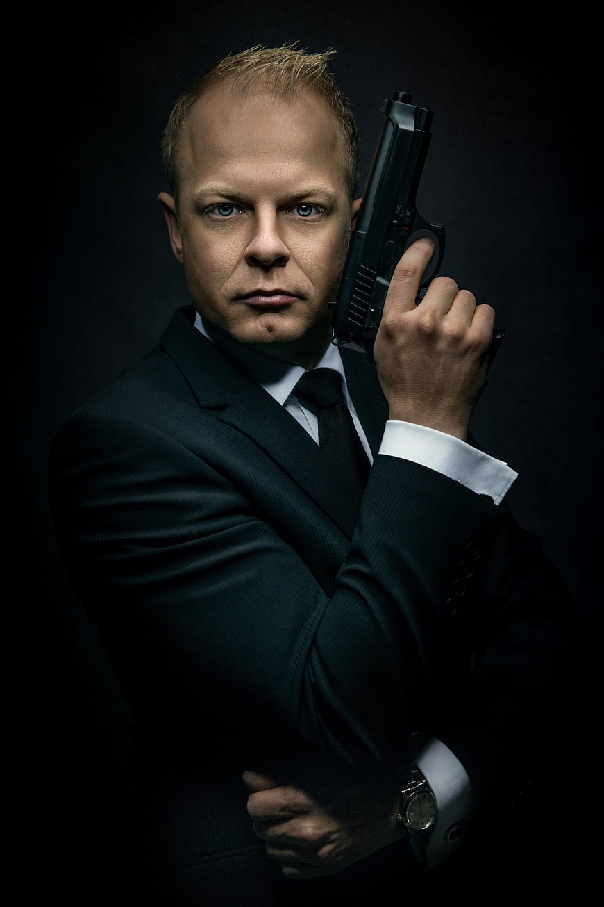 Dramatic Portrait of Man in Black Suit Holding Pistol