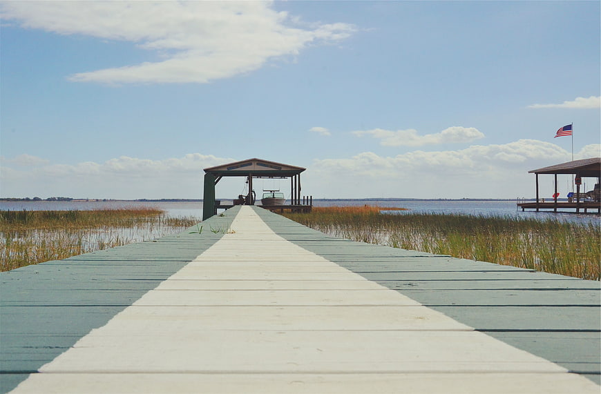 Wooden Dock Leading to Boat Shelter on Calm Lake