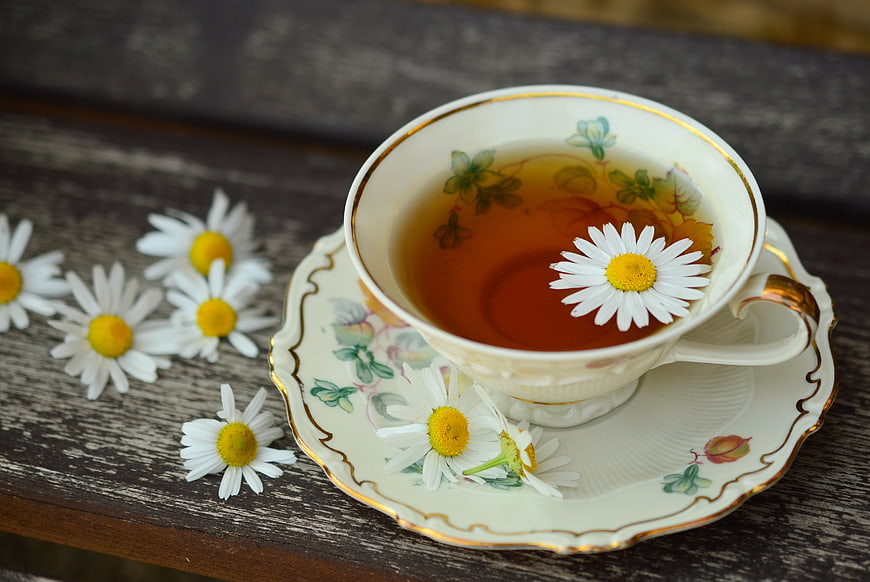 Vintage porcelain teacup with chamomile tea and flowers