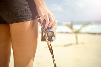 Woman Holding Vintage Camera on Sandy Beach