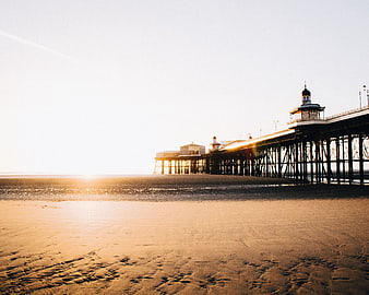 Sunrise over a historic pier on a sandy beach