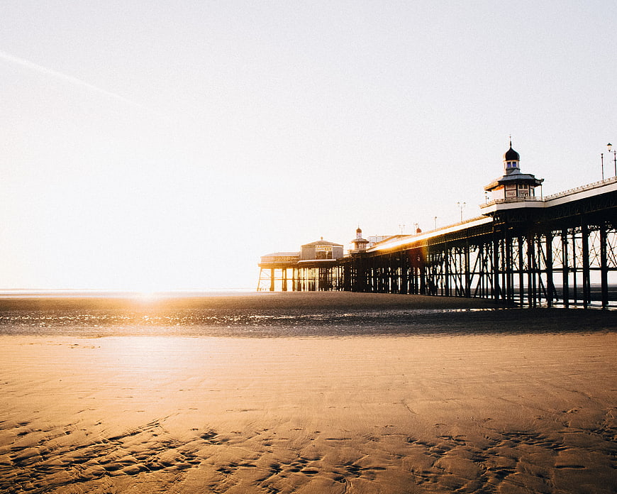 Sunrise over a historic pier on a sandy beach
