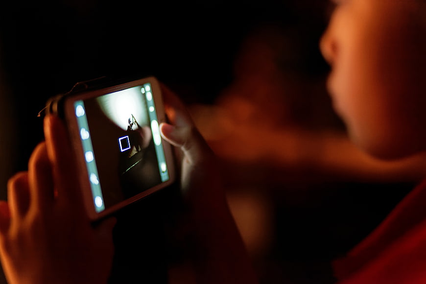 Child Taking Photo with Smartphone in Dark Room