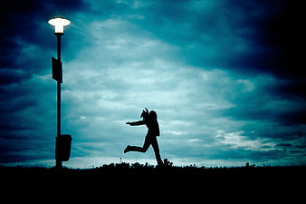 Silhouette of Woman Running Under Streetlight at Night