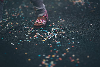 Child's feet walking on confetti-strewn asphalt