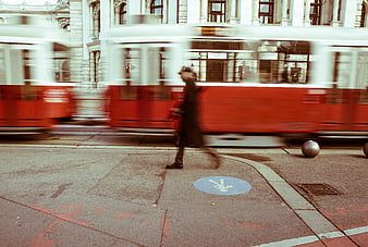 Man walking past blurred red tram in Vienna