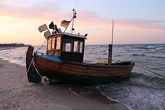 Wooden fishing boat on sandy beach at sunset