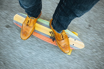Top view of man riding longboard in brown shoes