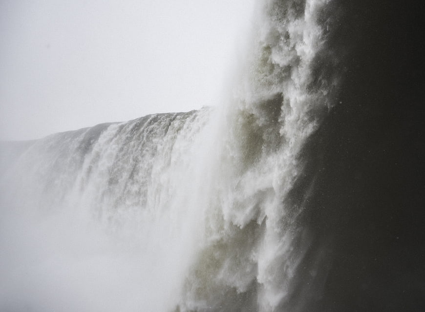 Powerful waterfall crashing into dark water with heavy mist